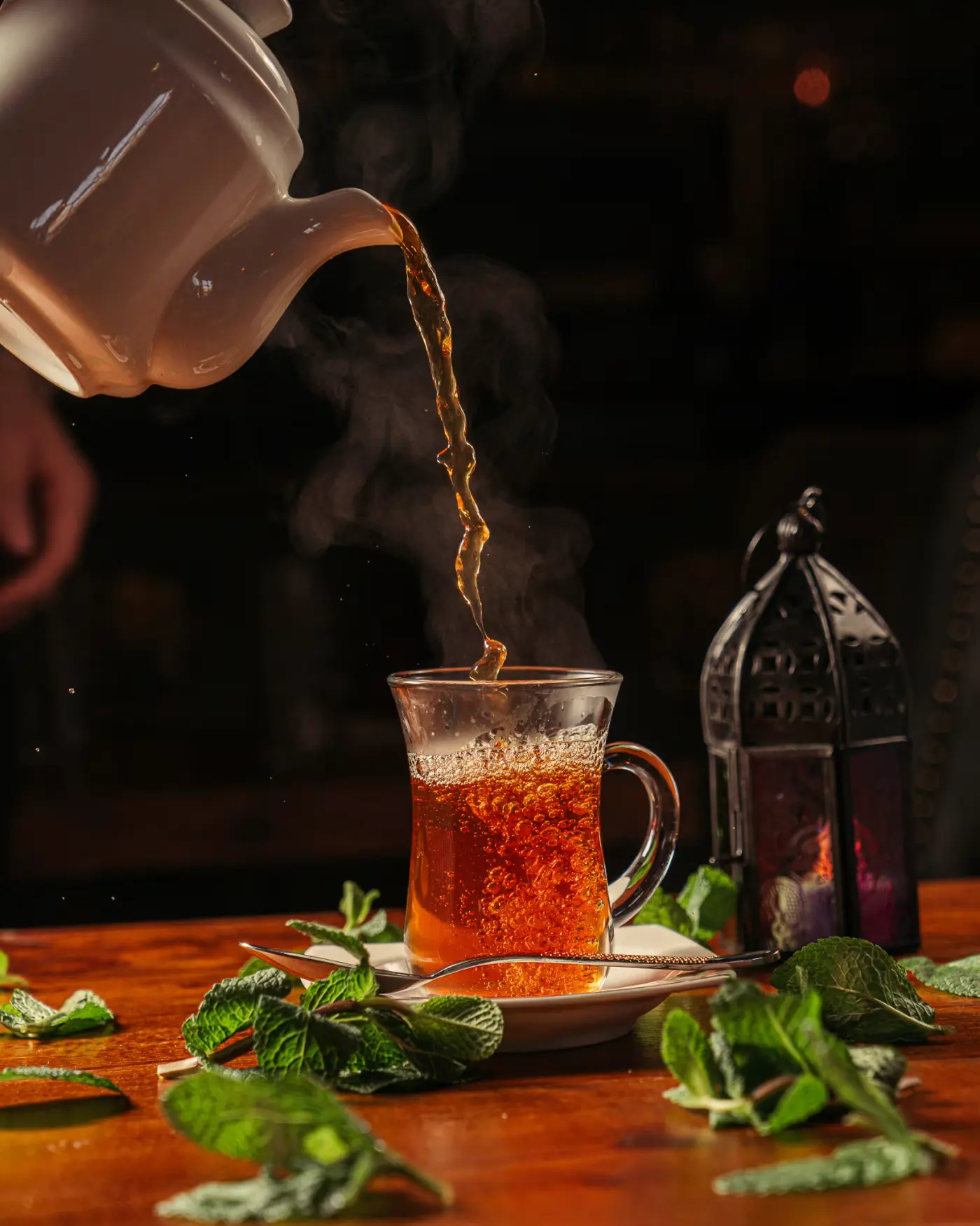Mint tea poured into a glass with lanterns behind at Beirut Restaurant. Photographed by Gorka Di Capitan (gorkadicapitan.com).