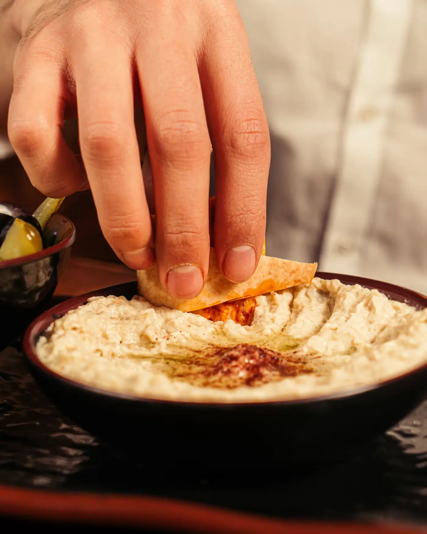 Hand dipping pita into hummus at Beirut Restaurant. Food photography by Gorka Di Capitan (gorkadicapitan.com).