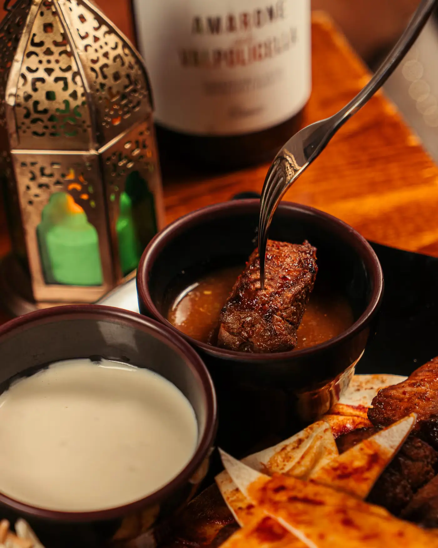 Fork dipping grilled meat into sauce beside a lantern at Beirut Restaurant, food photography session by Gorka Di Capitan (gorkadicapitan.com)