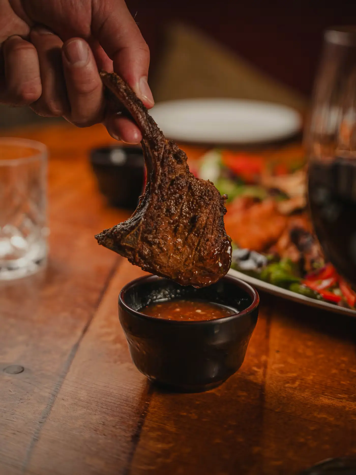 Grilled lamb chop dipped by hand into a bowl of sauce at Beirut Restaurant, food photography by Gorka Di Capitan (gorkadicapitan.com)