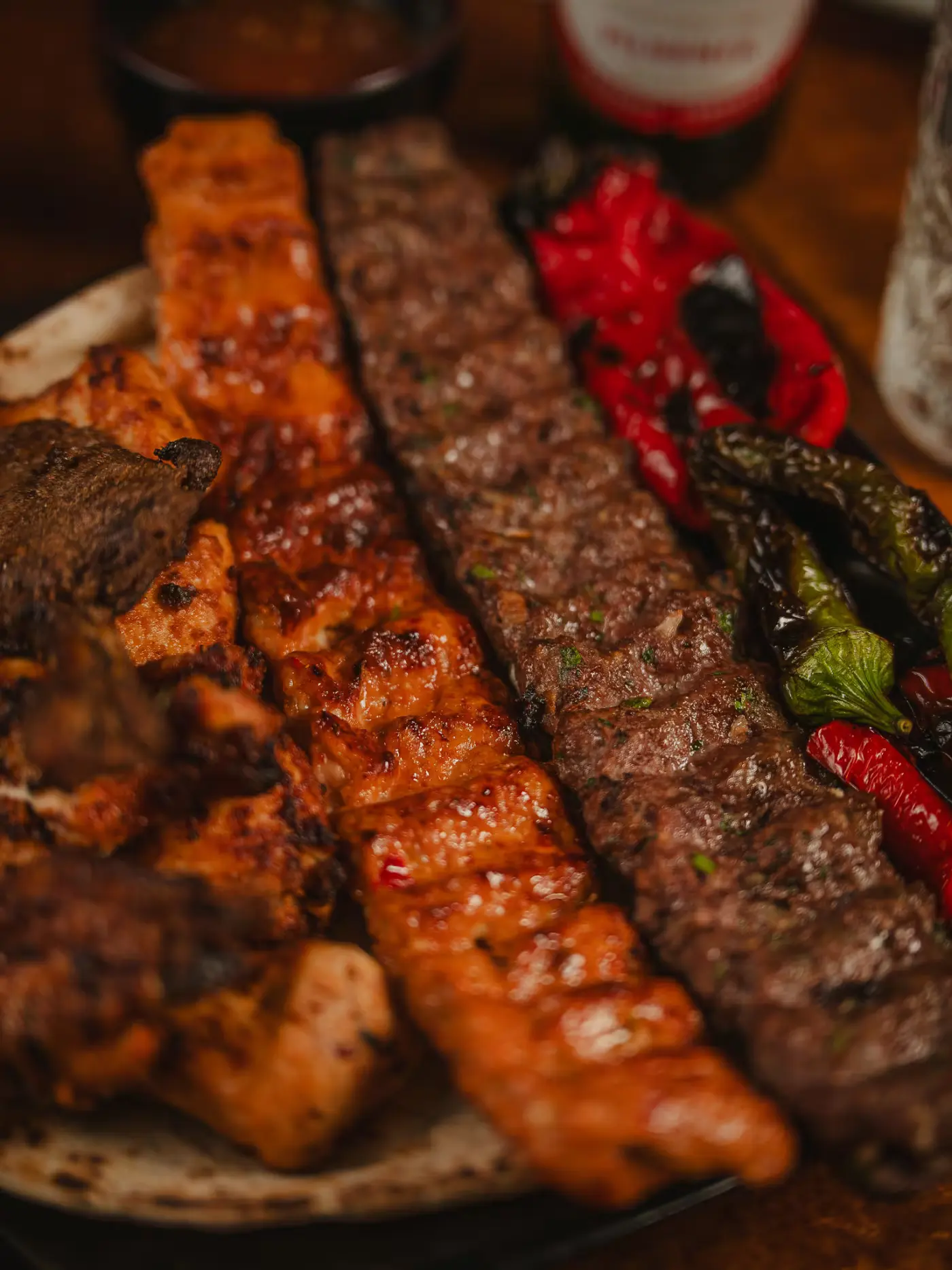 Close-up of chicken and lamb adana kebabs with charred chillies at Beirut Restaurant. Food photography by Gorka Di Capitan (gorkadicapitan.com).